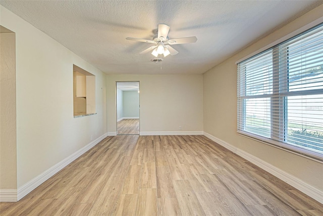 empty room with a textured ceiling, light wood-type flooring, and ceiling fan