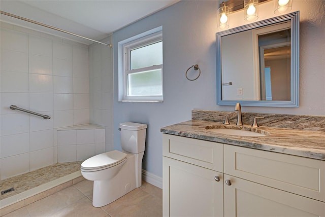 bathroom with tile patterned floors, vanity, toilet, and tiled shower