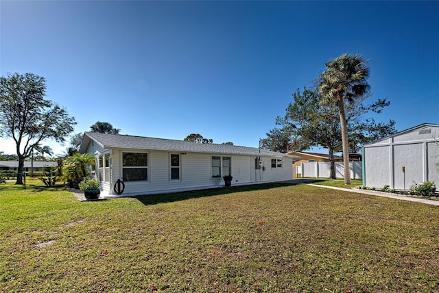 rear view of house with a lawn and a storage shed