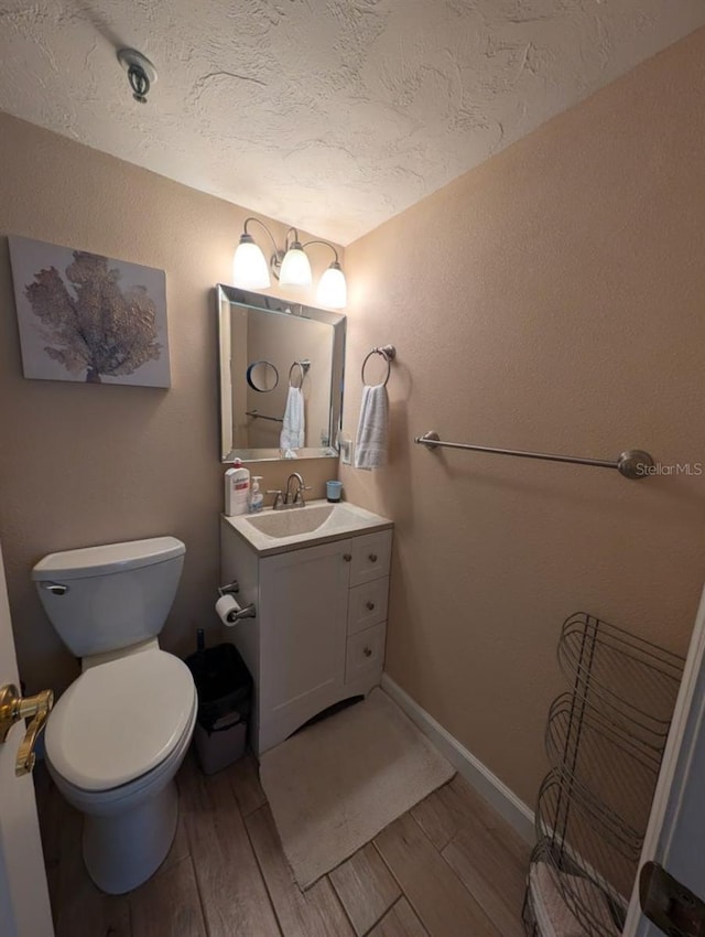 bathroom with a textured ceiling, vanity, hardwood / wood-style flooring, and toilet