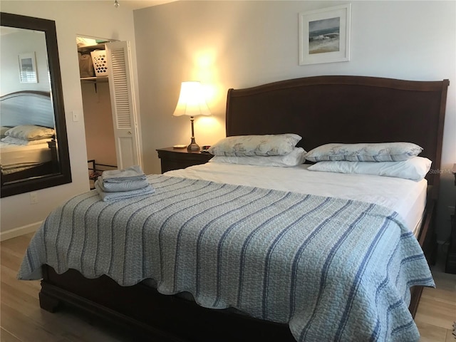 bedroom featuring a walk in closet, a closet, and hardwood / wood-style floors