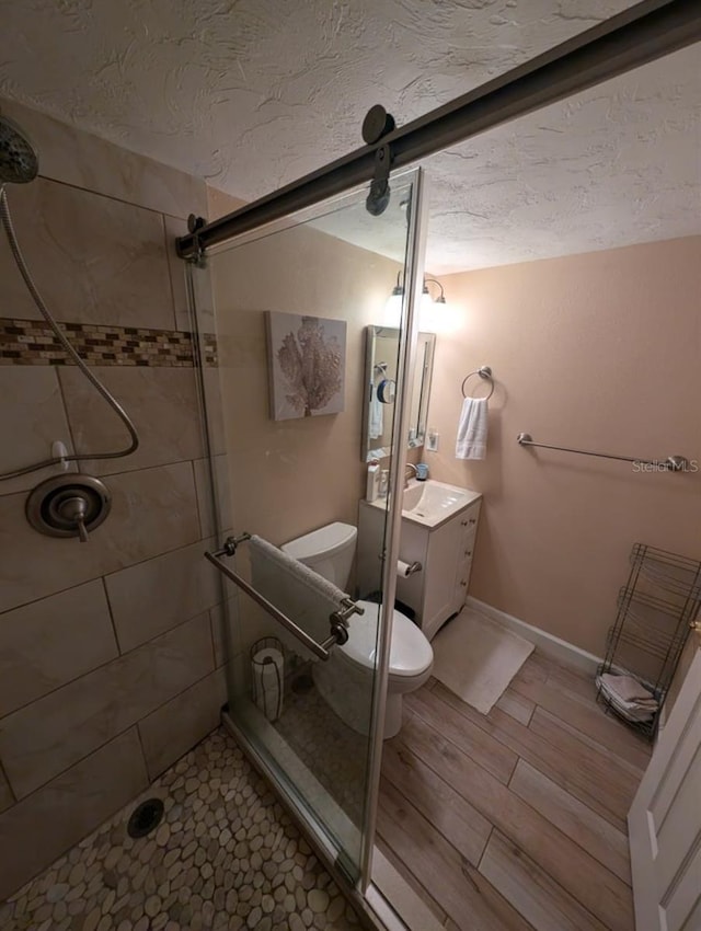 bathroom with walk in shower, vanity, a textured ceiling, and toilet