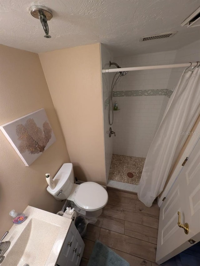 bathroom featuring toilet, vanity, a textured ceiling, and a shower with shower curtain