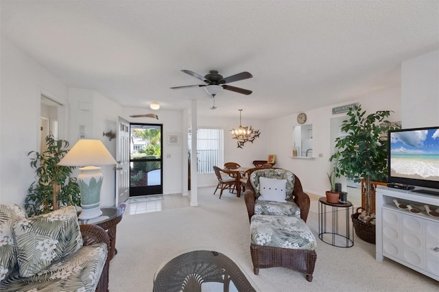 carpeted living room featuring a textured ceiling and ceiling fan with notable chandelier