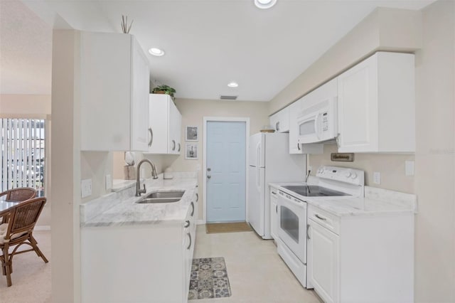 kitchen with white cabinets, white appliances, light stone countertops, and sink