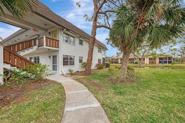 view of side of home with a yard and a balcony