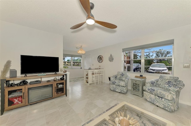 living room with ceiling fan and a textured ceiling