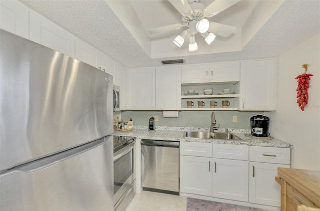 kitchen with ceiling fan, sink, stainless steel appliances, light stone counters, and white cabinets