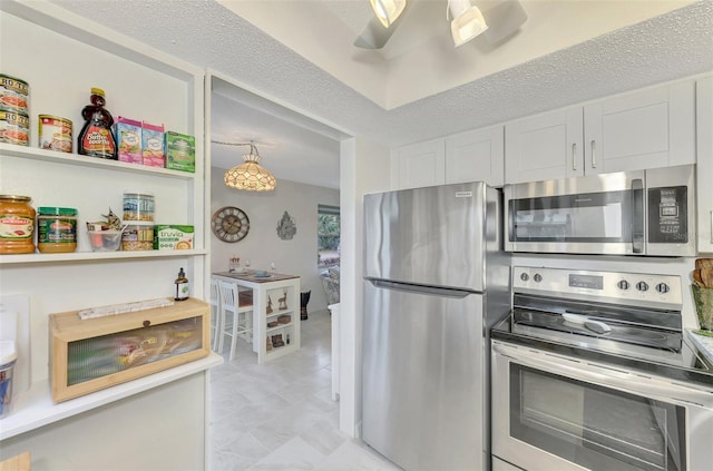 kitchen with white cabinetry, hanging light fixtures, stainless steel appliances, and a textured ceiling