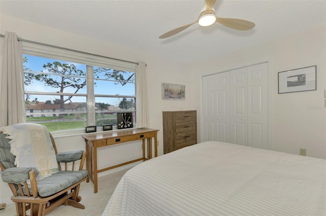 bedroom featuring ceiling fan, a closet, light tile patterned floors, and a textured ceiling