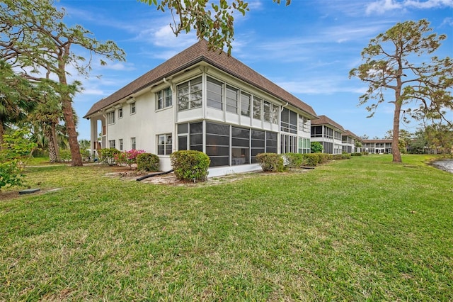 back of house featuring a lawn and a sunroom