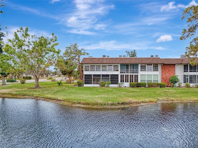 rear view of house featuring a lawn and a water view