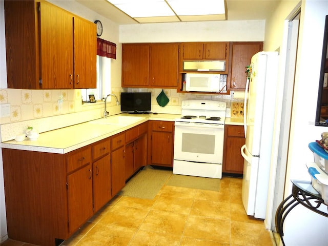 kitchen featuring decorative backsplash, white appliances, and sink