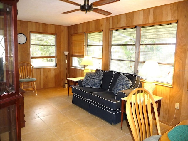 interior space featuring ceiling fan, wooden walls, and light tile patterned floors