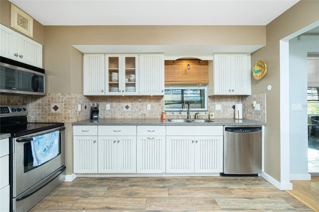 kitchen with white cabinets, sink, light stone countertops, appliances with stainless steel finishes, and tasteful backsplash