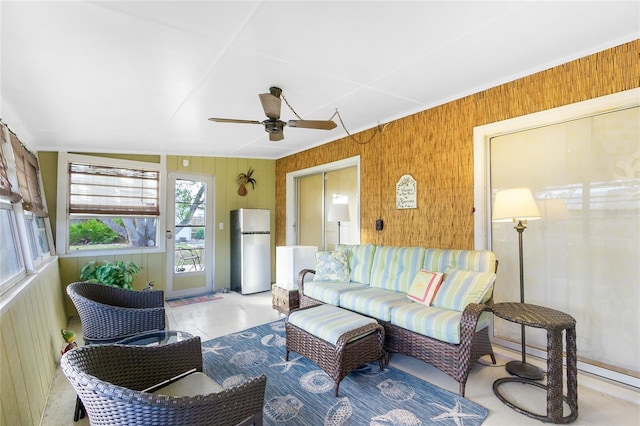 living room featuring ceiling fan and wood walls