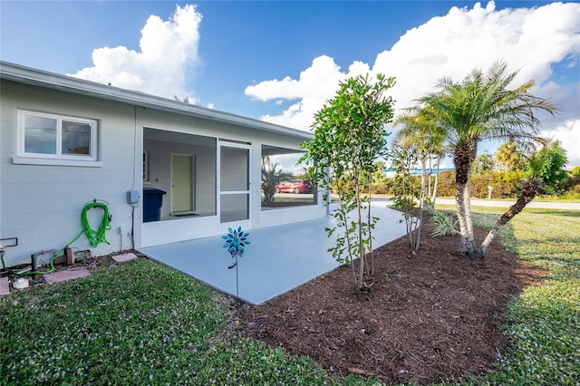 view of side of property with a patio and a lawn