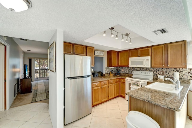 kitchen featuring light stone countertops, range with electric cooktop, a raised ceiling, sink, and stainless steel refrigerator