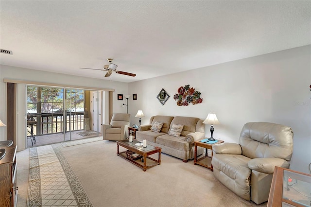 carpeted living room featuring ceiling fan and a textured ceiling