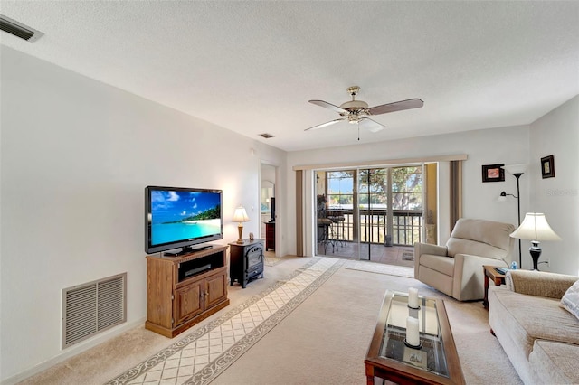 living room with ceiling fan, a textured ceiling, and light carpet