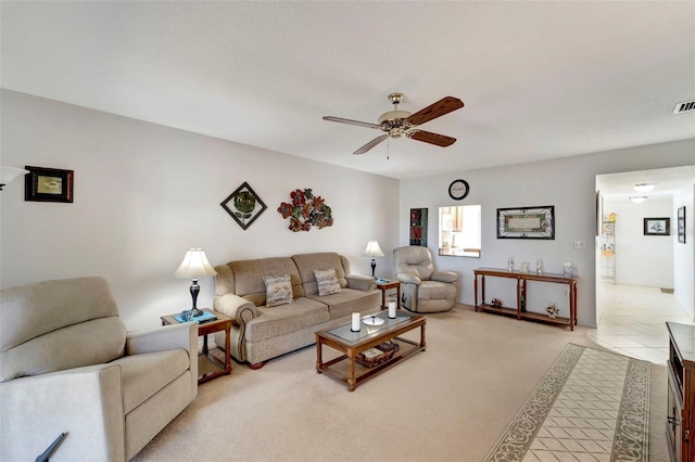 living room featuring ceiling fan, light colored carpet, and a textured ceiling