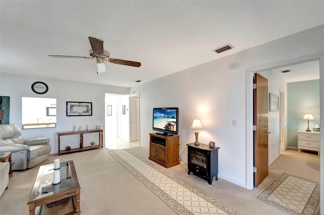 carpeted living room with ceiling fan and a textured ceiling