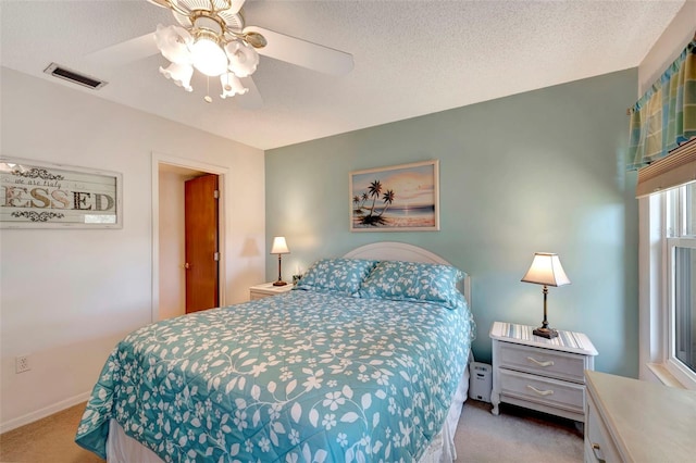 carpeted bedroom with ceiling fan and a textured ceiling