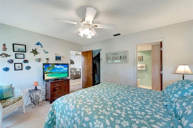 carpeted bedroom featuring connected bathroom, ceiling fan, and a textured ceiling