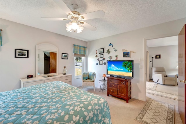 bedroom with ceiling fan, light carpet, and a textured ceiling