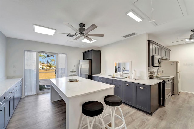 kitchen featuring sink, a kitchen breakfast bar, kitchen peninsula, light hardwood / wood-style floors, and appliances with stainless steel finishes