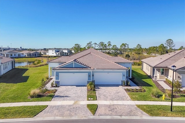 view of front of property featuring a water view, a garage, and a front lawn