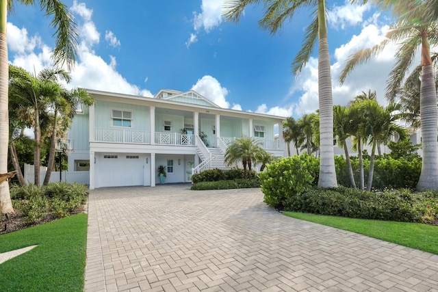 beach home with a porch, a front lawn, and a garage