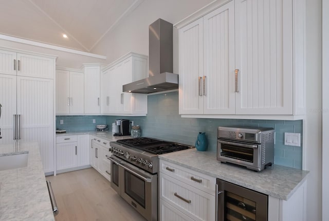 kitchen featuring white cabinets, backsplash, range with two ovens, wall chimney range hood, and wine cooler