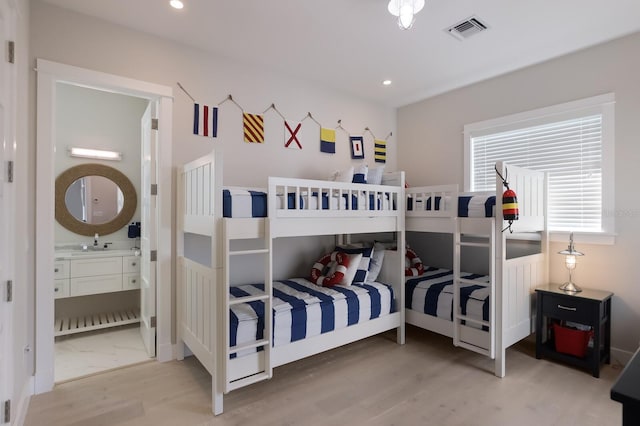 bedroom with hardwood / wood-style floors, connected bathroom, and sink