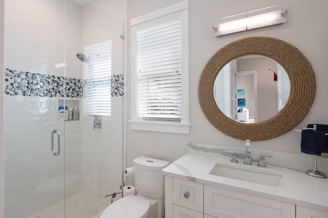 bathroom featuring toilet, vanity, and a shower with shower door