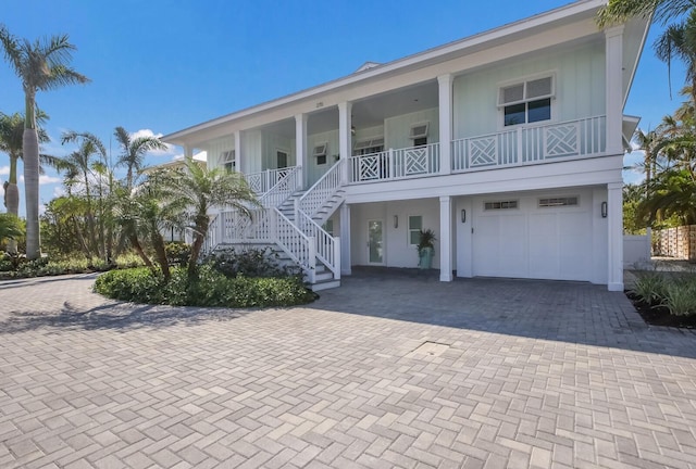 raised beach house featuring a porch and a garage