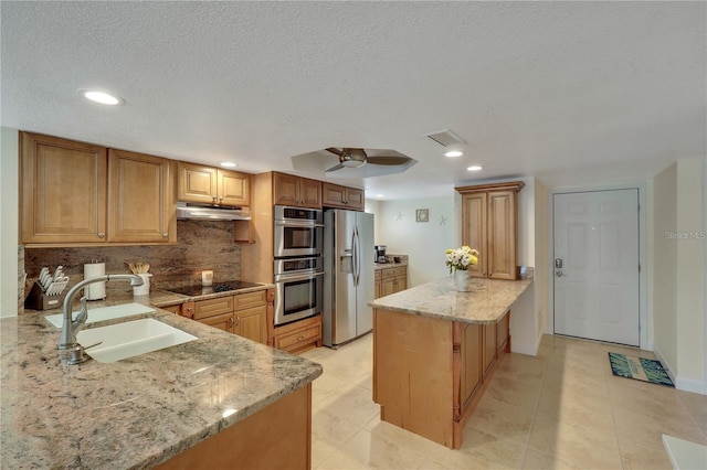 kitchen with sink, light stone counters, tasteful backsplash, kitchen peninsula, and appliances with stainless steel finishes