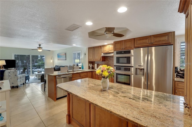 kitchen with light stone counters, stainless steel appliances, and kitchen peninsula