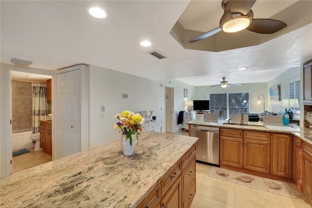 kitchen with sink, dishwasher, ceiling fan, light tile patterned floors, and light stone countertops