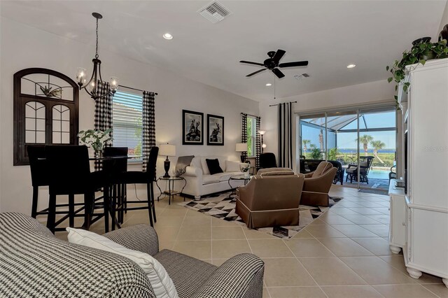 living room featuring light tile patterned floors, ceiling fan with notable chandelier, and a wealth of natural light