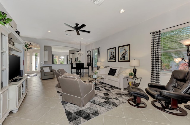 tiled living room featuring ceiling fan with notable chandelier