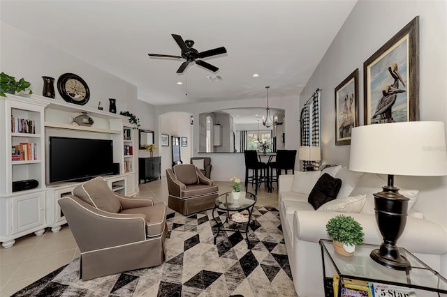 tiled living room with ceiling fan with notable chandelier