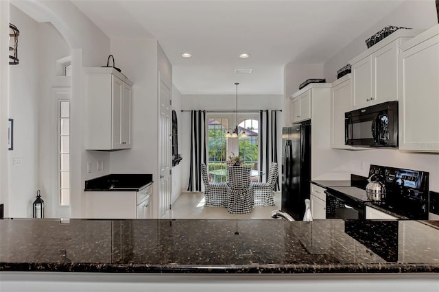 kitchen featuring dark stone counters, black appliances, white cabinets, decorative light fixtures, and kitchen peninsula