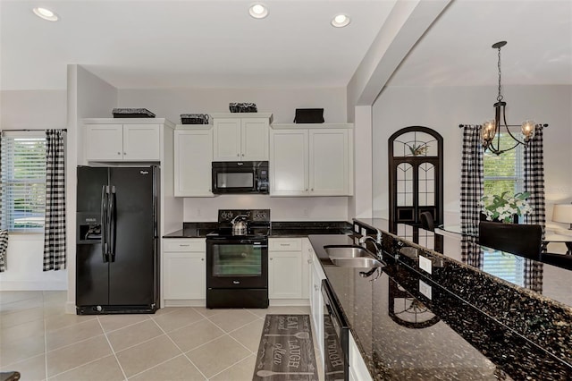 kitchen featuring dark stone counters, an inviting chandelier, black appliances, white cabinets, and sink