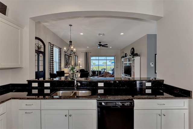 kitchen with dishwasher, white cabinets, ceiling fan with notable chandelier, sink, and dark stone countertops