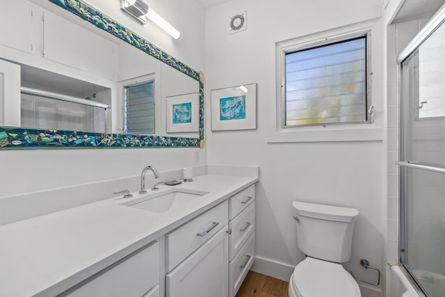 full bathroom with vanity, hardwood / wood-style flooring, bath / shower combo with glass door, and toilet