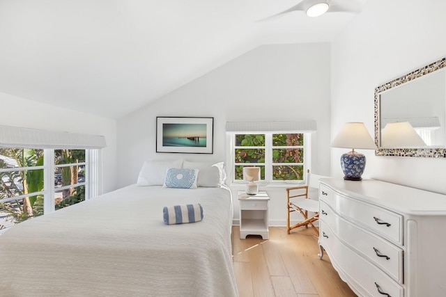 bedroom with ceiling fan, vaulted ceiling, multiple windows, and light wood-type flooring