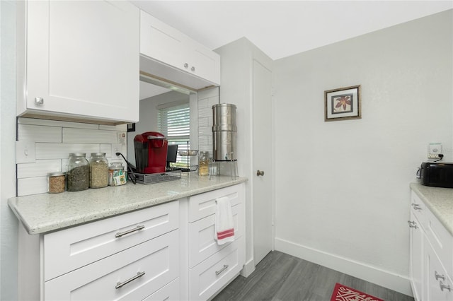 kitchen with dark hardwood / wood-style flooring, white cabinets, tasteful backsplash, and light stone counters