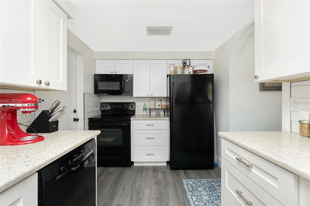 kitchen featuring light stone countertops, white cabinetry, black appliances, and dark hardwood / wood-style floors