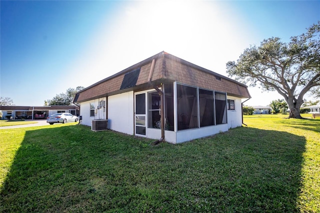 view of property exterior with a lawn, central AC, and a sunroom